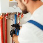 closeup of plumber working with water pipes while installing heating system in apartment